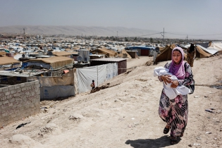  A mother carries her baby on her way to the medical center of the camp.