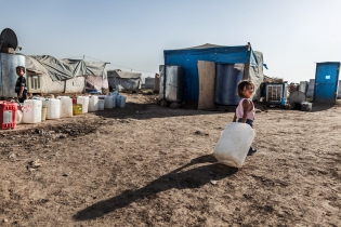  A young refugee drags her empty container on her way to water supply.